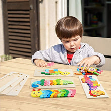 Young boy assembling colorful wooden animal-shaped puzzles on a light wooden table outdoors in daylight