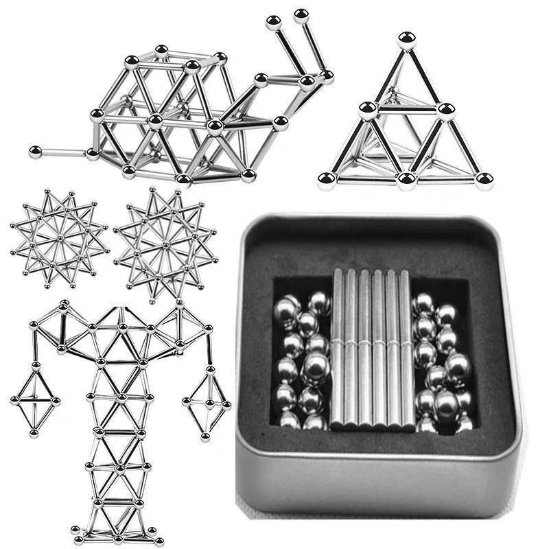 Magnetic silver spheres and rods arranged into geometric shapes including a snail, a pyramid, and a humanoid figure with a storage tin nearby