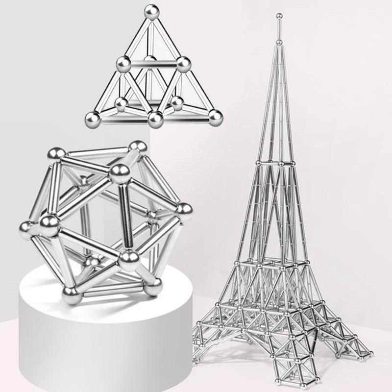 Silver magnetic building sticks and spheres assembled into geometric shapes and an Eiffel Tower model on white surface
