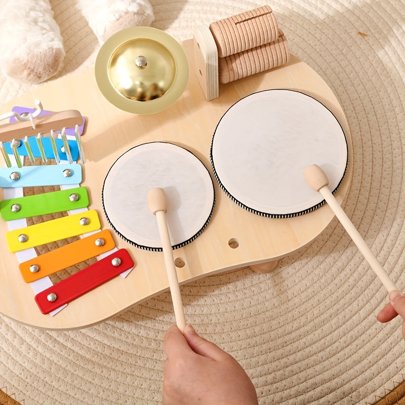 Child’s hands playing on wooden toy drum set with colorful xylophone, gold bell, and wooden castanets on round rug