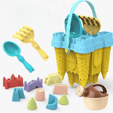 Yellow and blue castle-shaped sand bucket with matching shovel, rake, watering can, and colorful sand molds on white background
