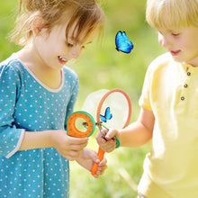 Two young children outdoors catching blue butterflies with orange-handled magnifying glass and net on green grass background
