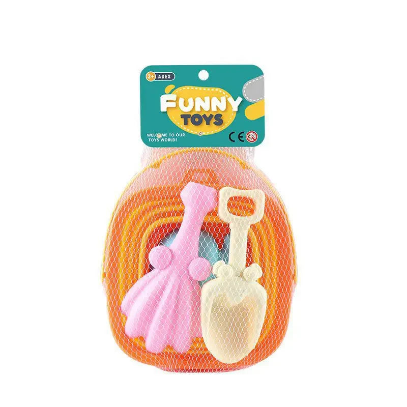 Children’s beach sand play set including pink rake, cream shovel, and orange tray packed in white mesh bag