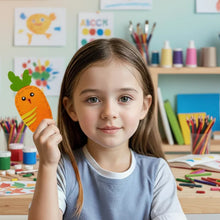 Young girl holding an orange felt carrot craft with a smiling face in a colorful art and craft room