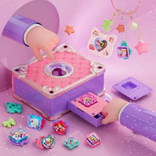 Hands playing with colorful plastic charms and a pink and purple toy music box on a pink surface