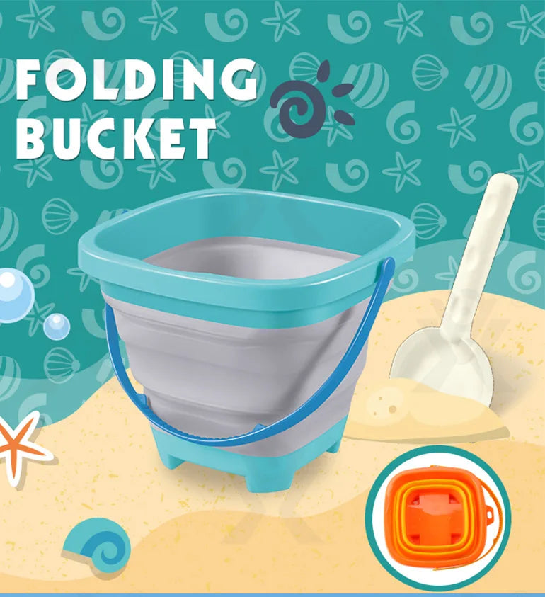 Collapsible silicone beach bucket with blue handle and teal rim next to white plastic shovel on sandy background