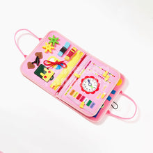 Pink busy board with colorful buttons, knobs, zippers, and shapes for toddler sensory and fine motor skill play